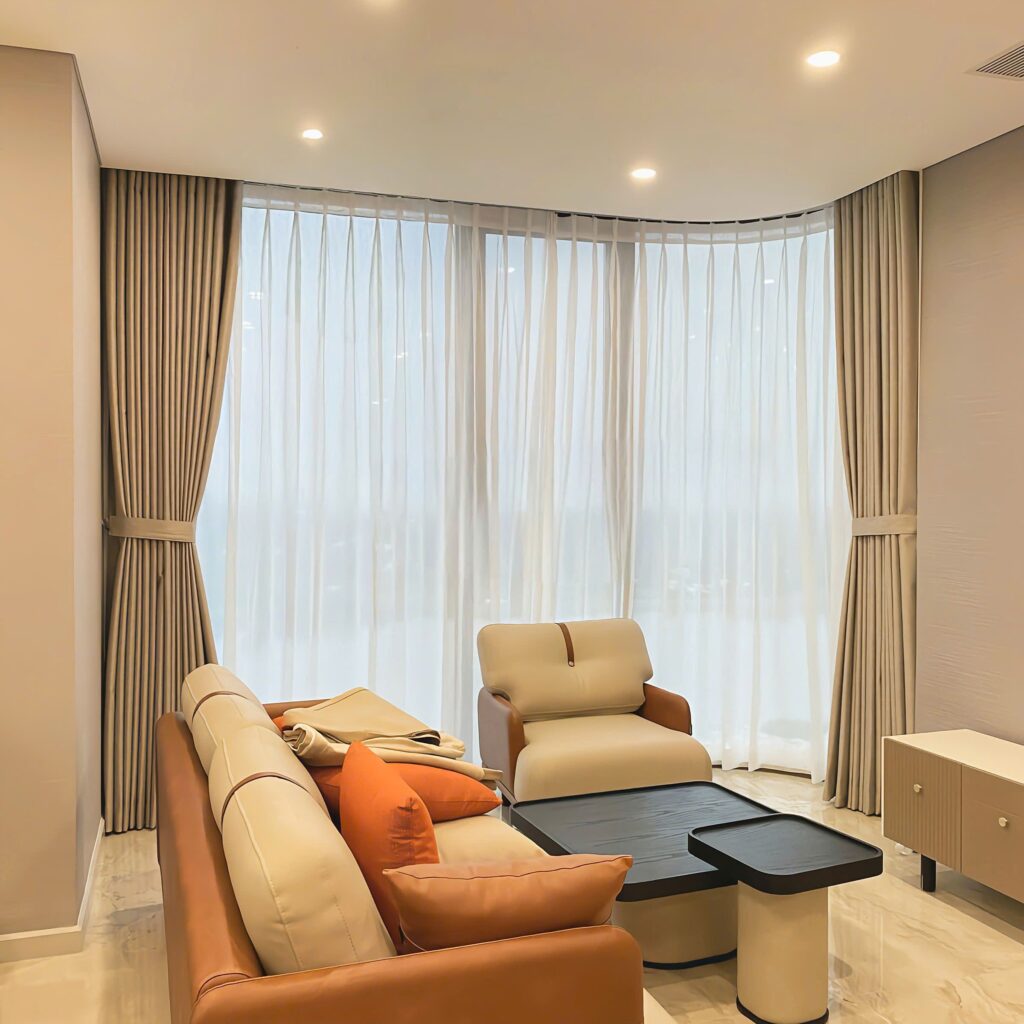 Phòng khách hiện đại với cửa kính góc, ray rèm uốn cong ôm sát tường, tạo cảm giác liền mạch và rộng mở.