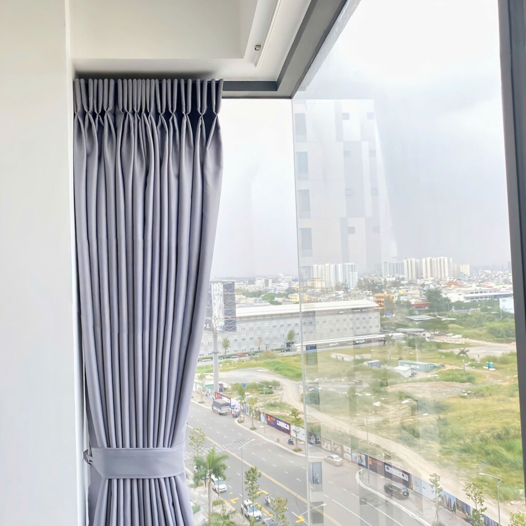 Phòng khách hiện đại với cửa kính góc, ray rèm uốn cong ôm sát tường, tạo cảm giác liền mạch và rộng mở.